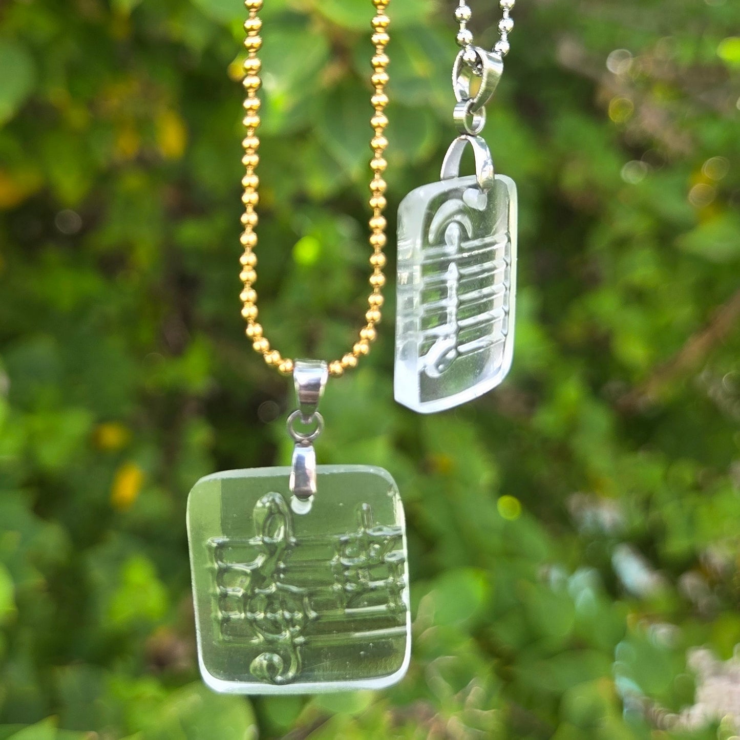 Recycled vodka bottle glass music note pendant necklaces on gold and silver ball chains.