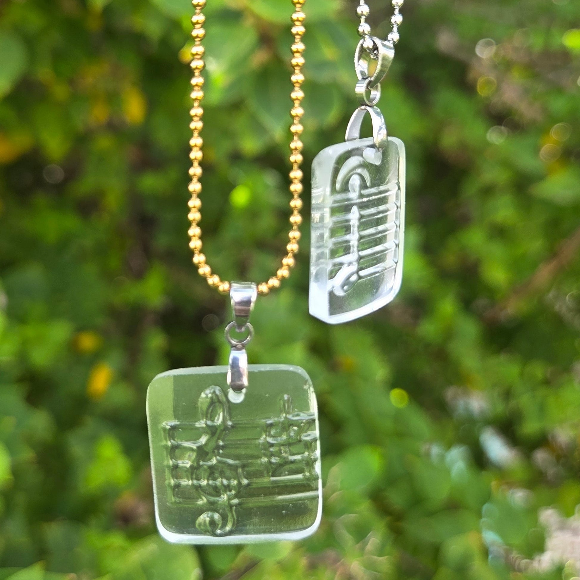 Recycled vodka bottle glass music note pendant necklaces on gold and silver ball chains.