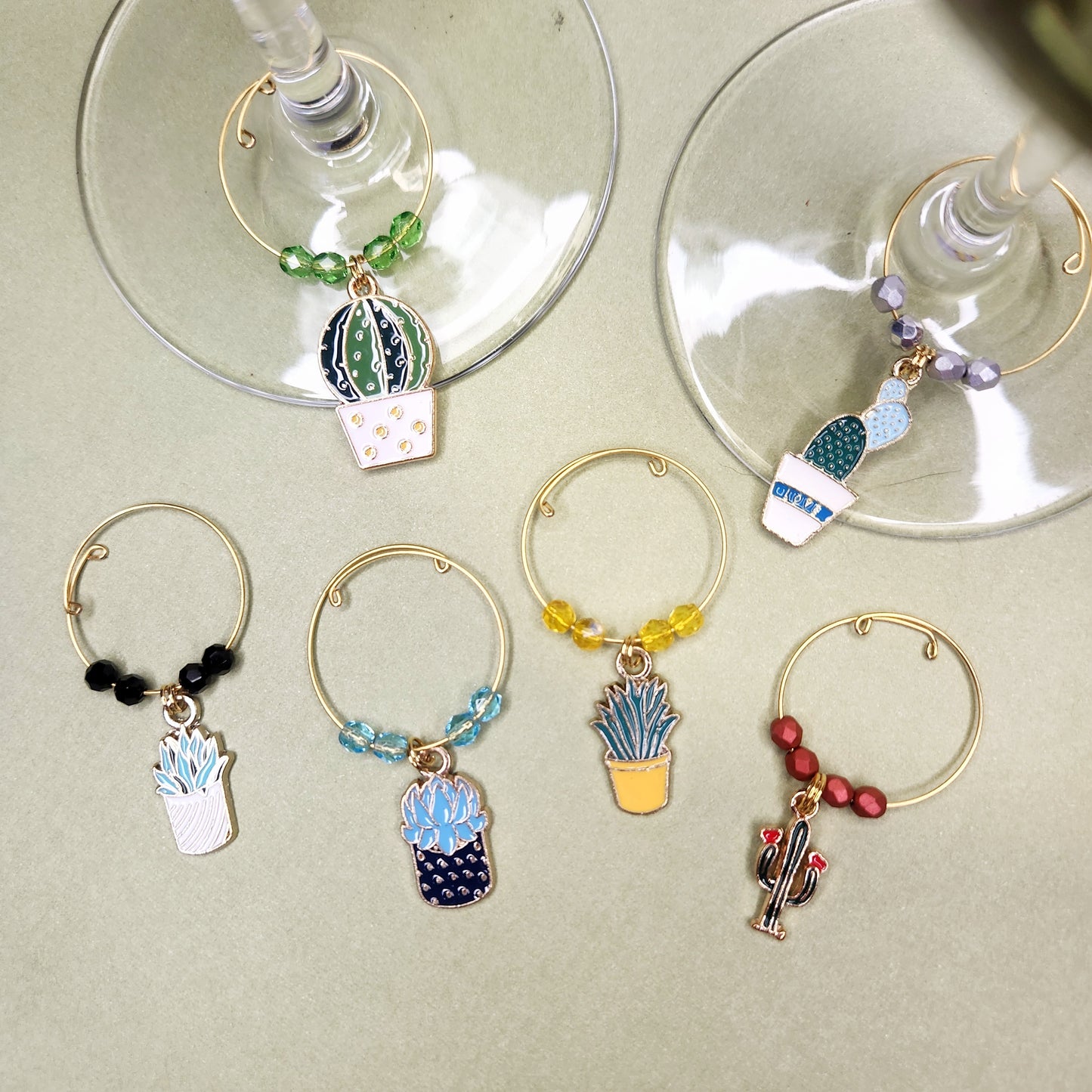  A variety of cactus and succulent-themed wine glass charms on wine glasses, demonstrating their fun and functional design for party settings.