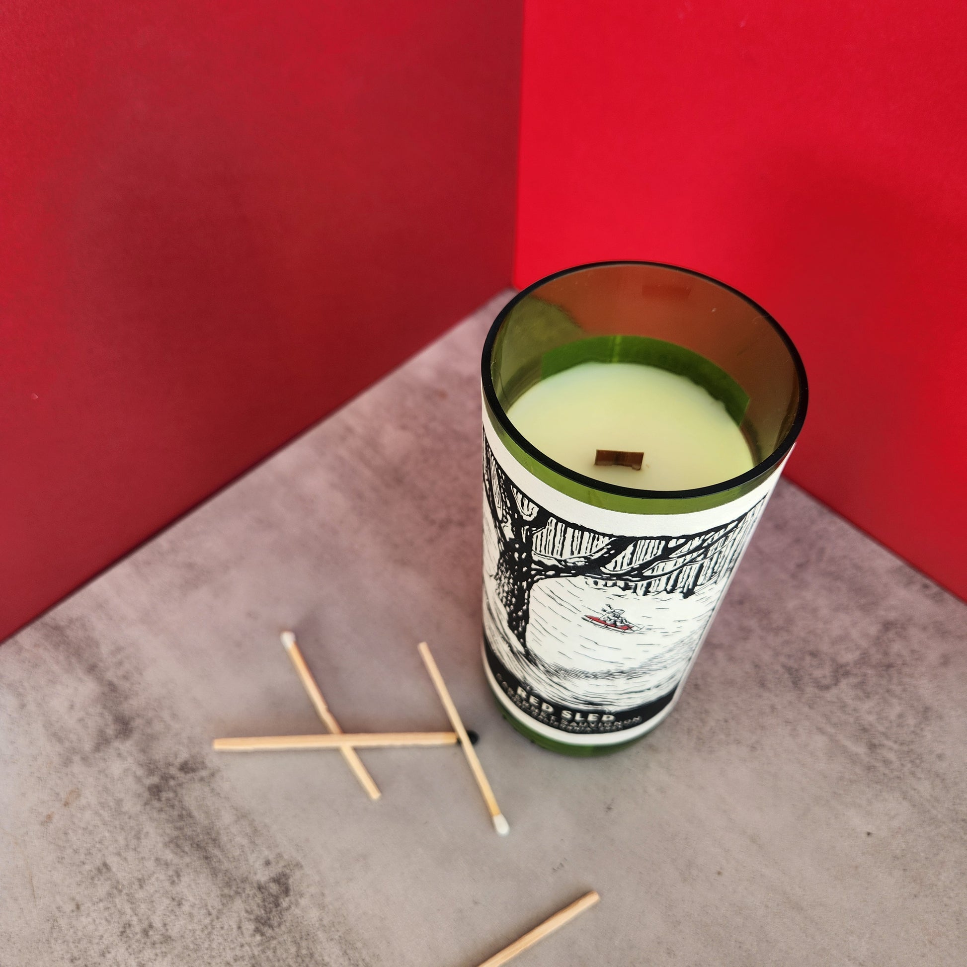 Angled top view of the Fir Tree candle in a recycled Red Sled wine bottle, highlighting the clean finish and rustic winter charm.