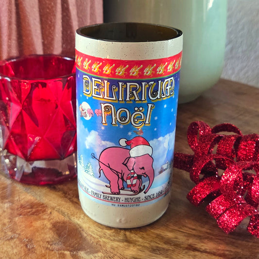 Delirium Noel beer can with festive design on a wooden surface with red glass and bow.