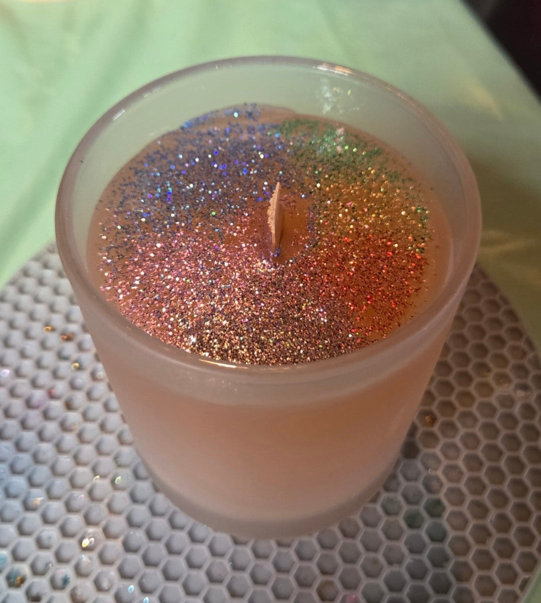 Candle in a glass container on a textured surface with a blurred background