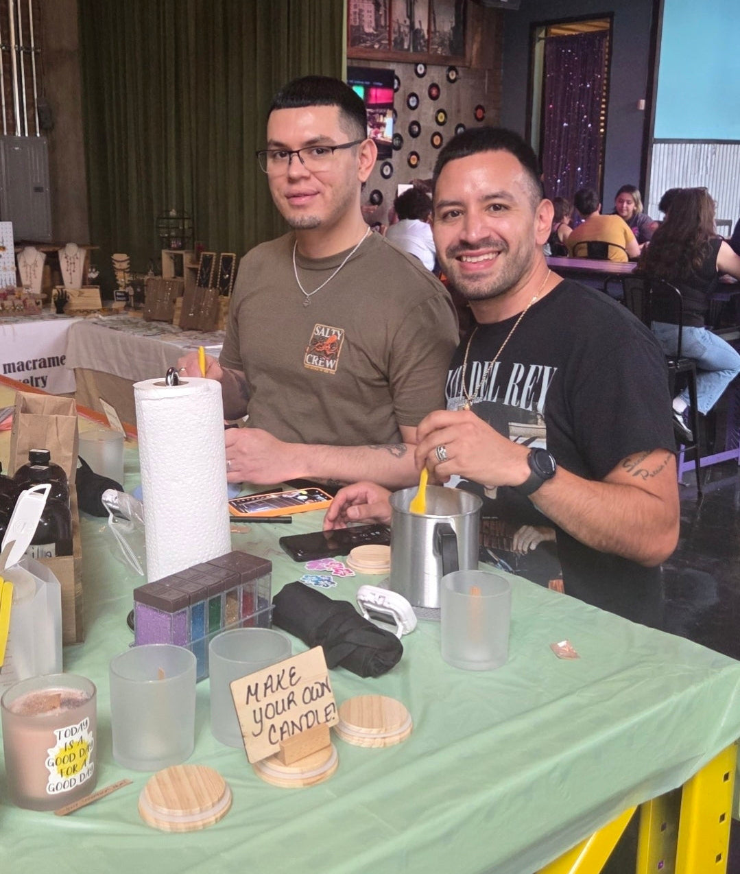Two men sitting at a table with a green tablecloth in an indoor setting.
