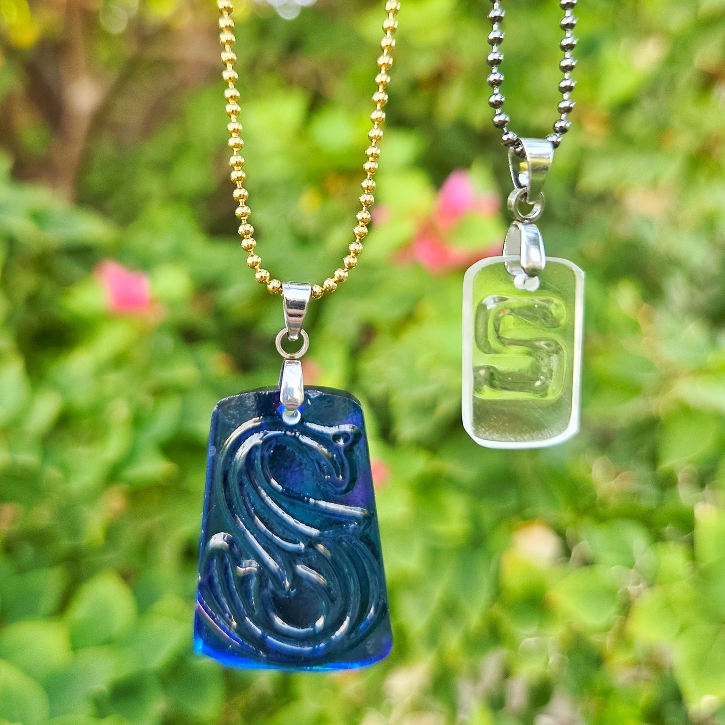 Two Letter S initial necklaces made from recycled bottle glass, including blue water bottle glass and clear whiskey bottle glass