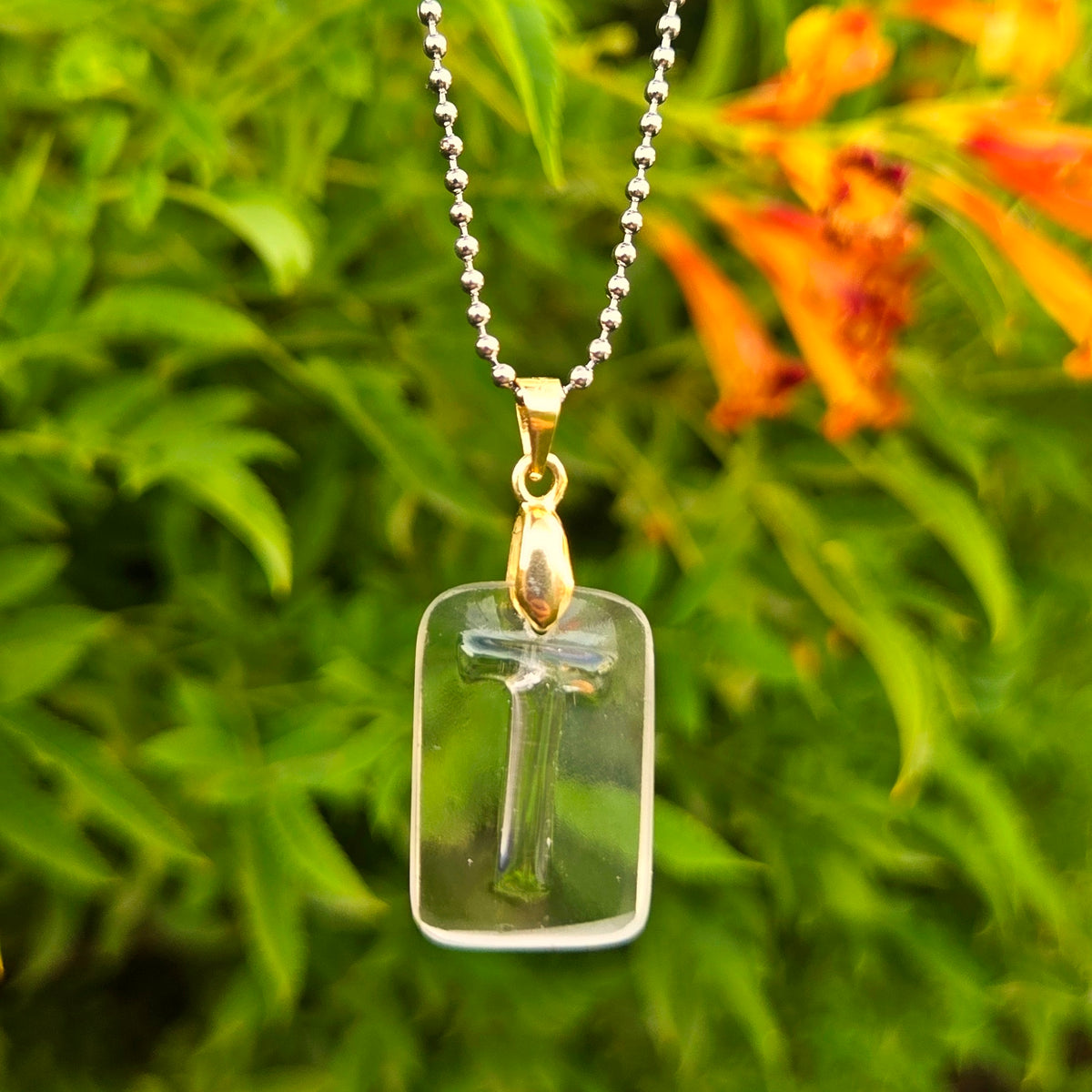 Letter T initial necklace made from clear recycled whiskey bottle glass with original raised lettering