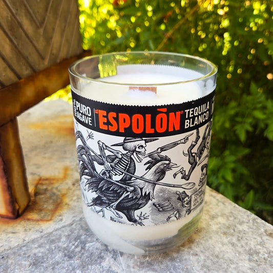 Glass with Espolón Tequila Blanco label on a stone surface with greenery in the background