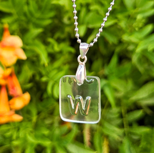 Letter W initial necklace made from clear recycled whiskey bottle glass with original raised lettering